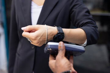 Woman client finishes food purchase by tapping the smartwatch against the POS device, using nfc...
