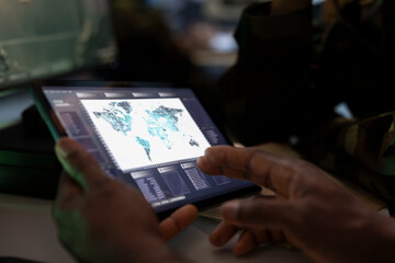 Military officer conducts tactical reconnaissance in war room, utilizing tablet for data analysis. Army professional uses satellite tech on digital device to look at aerial map, pinpointing targets