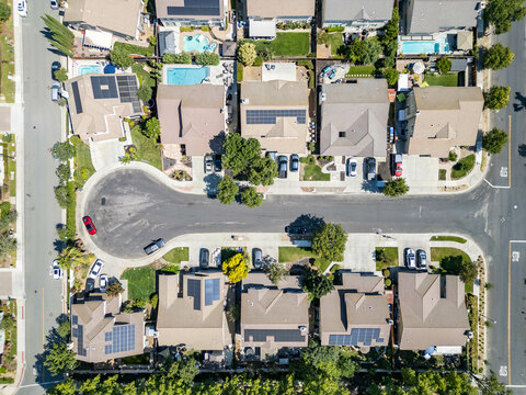Aerial view of suburban residential neighborhood with modern homes, rows of houses with solar panels and swimming pools, community living design urban infrastructure concept