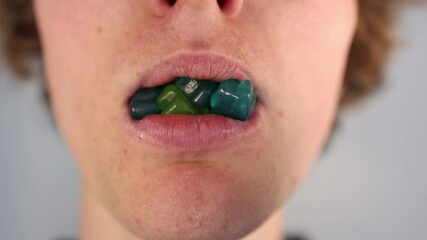 Eating colorful gummy bears with missing front teeth in an extreme closeup illustrating sugar addiction and consequences of poor dental hygiene