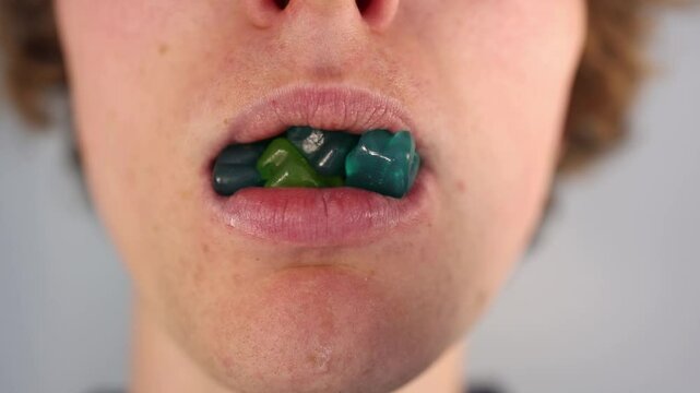 Eating colorful gummy bears with missing front teeth in an extreme closeup illustrating sugar addiction and consequences of poor dental hygiene