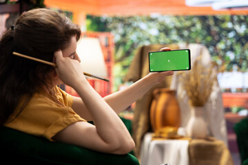 Painter admiring her creative masterpiece in art studio next to green screen, finishing her oil...