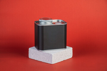 Black can for packaging with stylish props on red background.