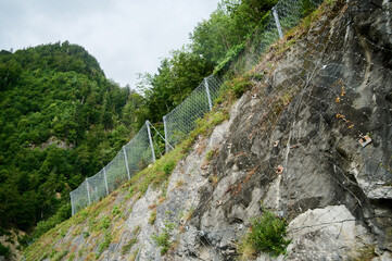 A sturdy fence lines a steep rocky slope, designed to protect the area from potential rockfall...