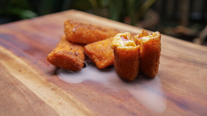 Risol mayonaise or Crispy fried breaded rolls with melted cheese and meat filling. Tasty snack served on wooden background with steam effect
