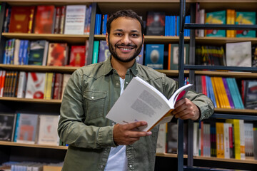 Young bearded dark-haired man reading a book and smiling
