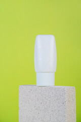 Plastic white tube for cream or lotion. Skin care or sunscreen cosmetic with stylish props on green background.