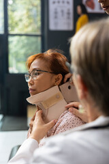Medical staff fixing cervical collar on woman with signs of neck trauma, physiotherapy and recovery...