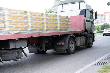 Large delivery truck transporting goods on an urban road with residential buildings in the...