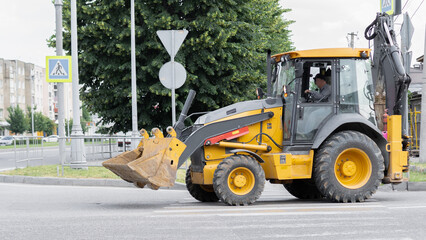 Construction vehicle operating on city street during daytime hours in an urban setting