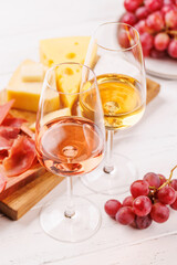 A delectable arrangement of various cheeses, fresh grapes, prosciutto and wine