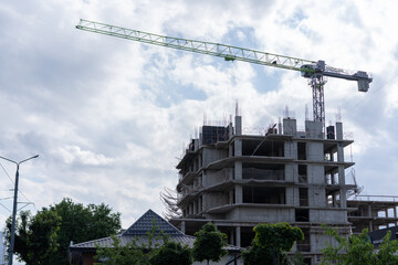 Construction site features a tall crane working on a multi-story building as clouds gather in the sky during the afternoon