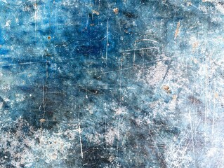 Weathered and aged blue concrete surface with pitted chips and long scratches making a grungy background texture
