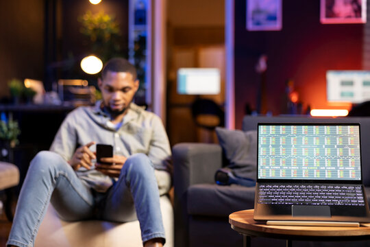 Black adult monitoring a screen to review stock market online data, reviewing day trading strategies and financial diagrams. Remote worker tracks online investments and economic trends.