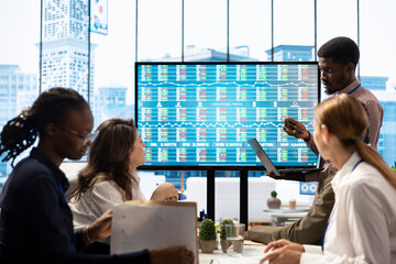 Business associates collaborating at the conference table in boardroom, utilizing smart technology...