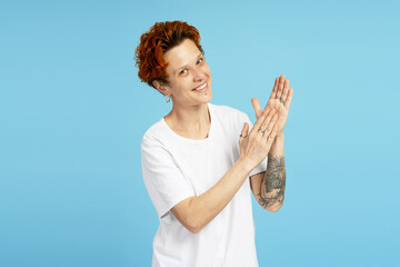 Happy woman applauding, clap hands and looking joyful, standing over blue background