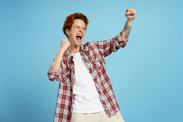 Happy woman with piercing winner screaming celebrating win isolated on blue background