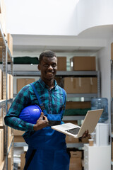 Black male employee examine labeled parcels on shelves in a storage unit depot. Logistics services...