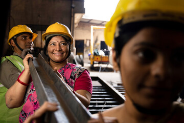 Female iron Factory Worker at work moving iron poles.