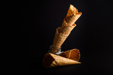 Multiple waffle cones are arranged in a stylish stack, showcasing their crispy texture against a...