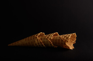 A single waffle cone sits gracefully on a dark background, showcasing its crispy texture and unique...