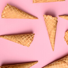 Waffle cones are arranged on a soft pink surface, highlighting their crisp texture and ready for...