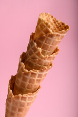 Four stacked waffle cones highlight their crisp texture against a soft pink background, ideal for holding delicious ice cream treats