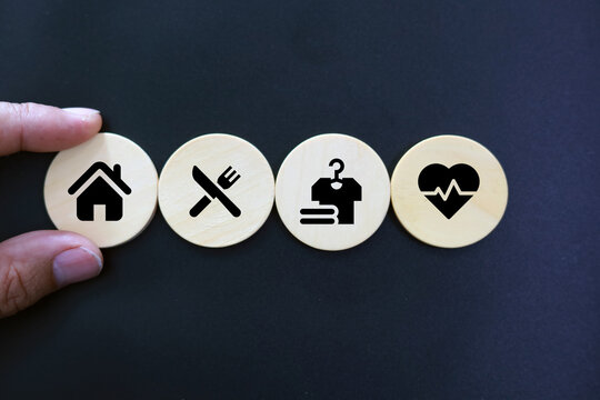 wooden cube with icons of food, Clothing, housing, medical bag, four basic human needs concepts. The Four Basic Material Needs of the Human Being