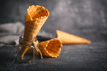 Waffle and sugar cones are artfully arranged in a glass jar, showcasing their texture against a...