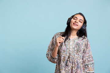 Happy woman playing electronic music and waving hand in the air, doing groovy dance moves in the...