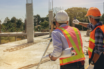 Engineer and surveyor worker working with theodolite transit equipment at outdoors construction site