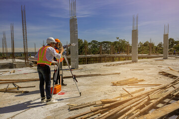 Engineer and surveyor worker working with theodolite transit equipment at outdoors construction site