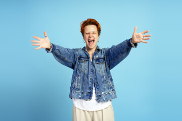 Happy energetic young woman with piercings raising hands in victory, looking at camera