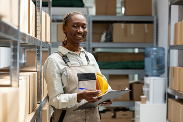 African american woman sorting retail boxes for dispatch from depot racks, manual work job....