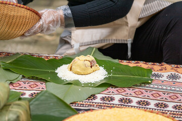 Woman with traditional Tay dress Making (wrapping) Tet Cake, the Vietnamese lunar new year Tet food...