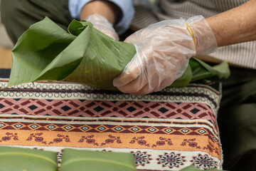 Woman with traditional Tay dress Making (wrapping) Tet Cake, the Vietnamese lunar new year Tet food...