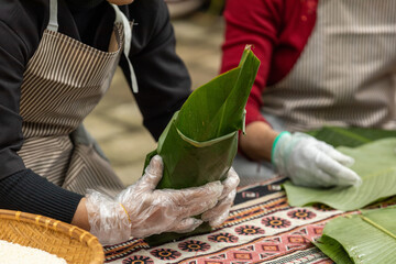 Woman with traditional Tay dress Making (wrapping) Tet Cake, the Vietnamese lunar new year Tet food...
