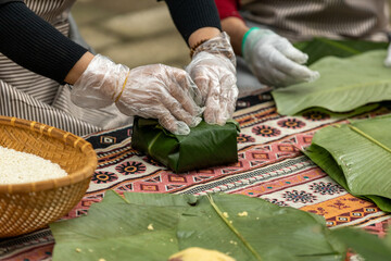 Woman with traditional Tay dress Making (wrapping) Tet Cake, the Vietnamese lunar new year Tet food...