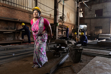 Woman moves an empty pallet jack through an industrial hall.