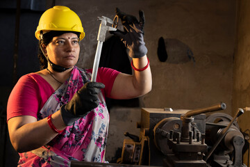 Female maintenance engineer with mechanic measuring using micrometer at workshop