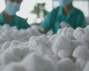 Cotton fibers are being processed in textile factory, showcasing intricate work involved in garment production. Workers in protective masks focus on their tasks, emphasizing safety and dedication