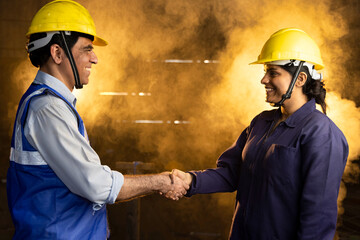 Two industrial engineers man and woman shake hands to celebrate success work together.