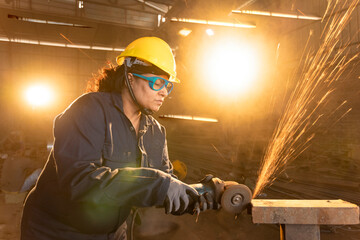 Side view portrait of mature female worker cutting metal at industrial plant