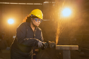 Side view portrait of mature female worker cutting metal at industrial plant
