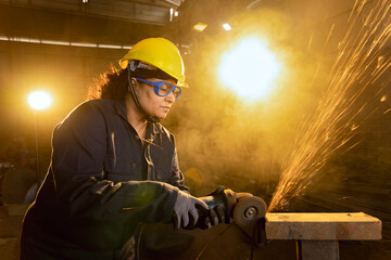 Side view portrait of mature female worker cutting metal at industrial plant