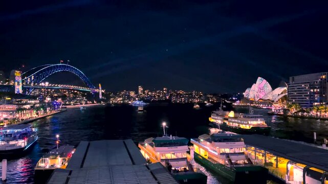 Sydney, Australia -June 11, 2025: 4k Video -Colourful lights illuminate Sydney Skyline at Circular Quay Ferry Terminal during Vivid Festival in Sydney Harbour.