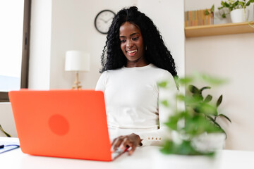 Young black woman working on laptop from home office. Business and working at home concept