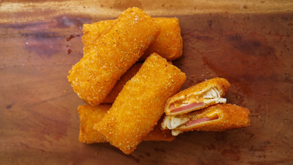 Risol mayonaise or Crispy fried breaded rolls with melted cheese and meat filling. Tasty snack served on wooden background with steam effect