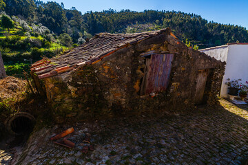 A rustic stone building with a tiled roof sits in the foreground