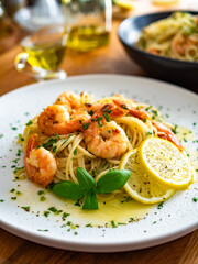 Spaghetti with fried shrimps, olive oil and parsley on wooden table	